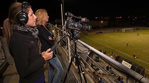 Students recording soccer game at night